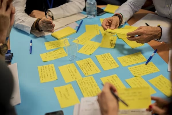 Team collaborating on a blue surface with sticky notes during a brainstorming or planning session