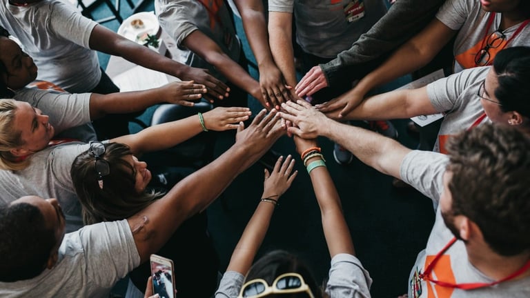 Diverse group of people with hands stacked together in circle, viewed from below, showing teamwork and unity